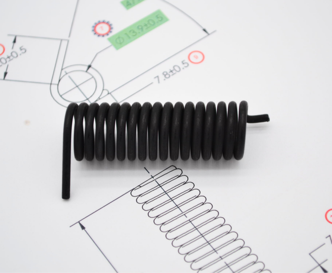 Image of a porotype spring sitting on top of a piece of paper with design of the spring.