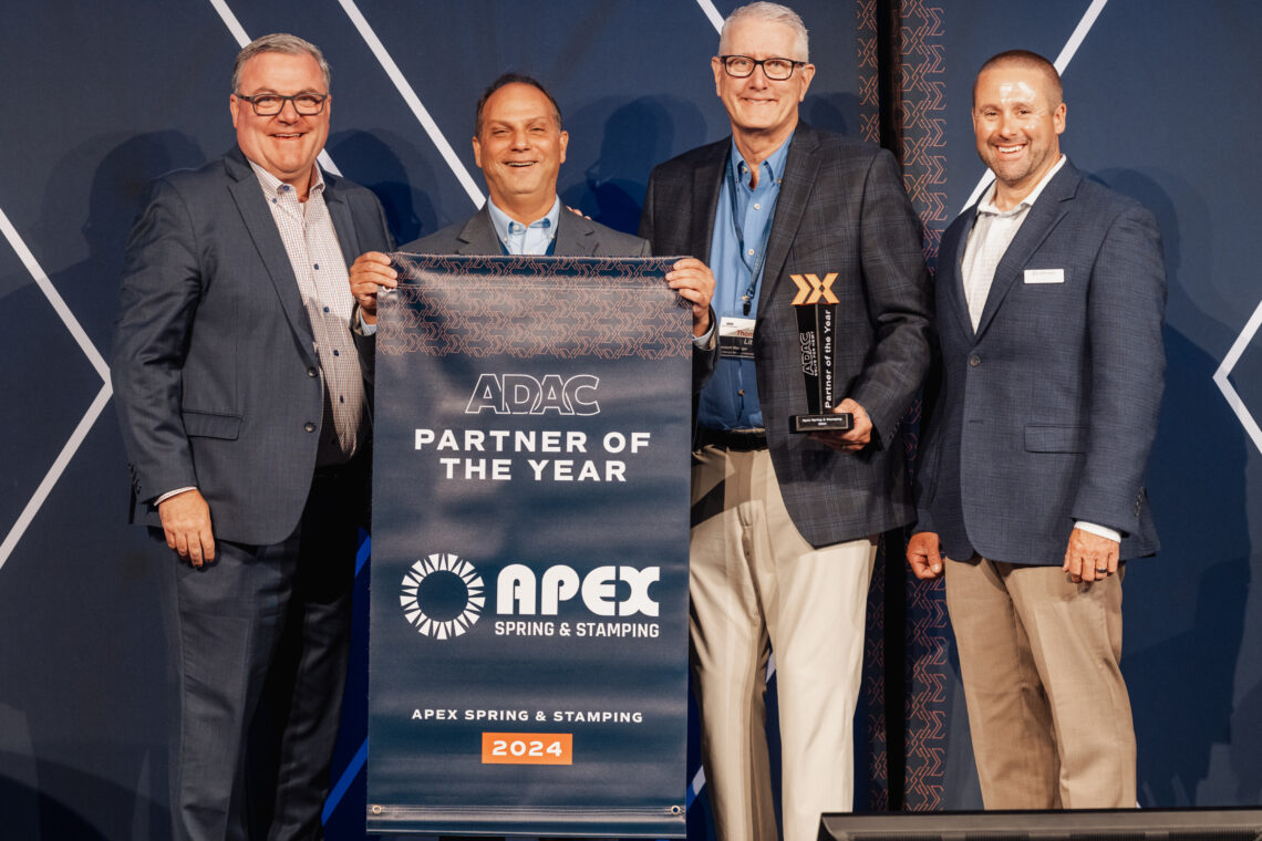Image of two Apex employees receiving a Banner in recognition of being named 2024 ADAC Partner of the Year